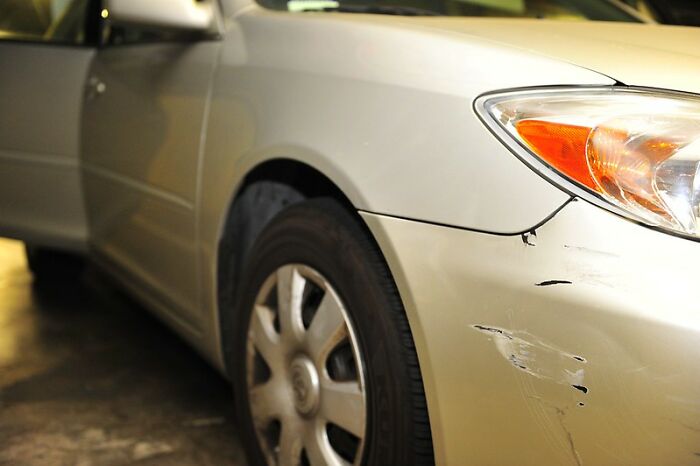 Close-up of a scratched car bumper with a windshield note attached, highlighting startling windshield notes found by drivers.