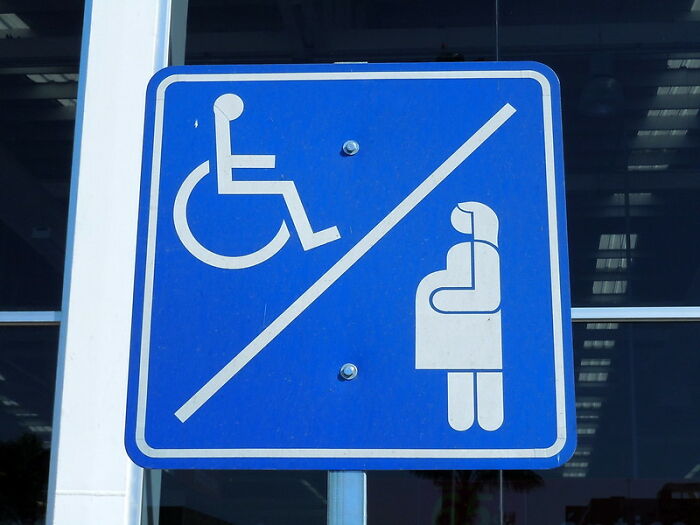 Blue parking sign showing handicap and pregnant woman icons separated by a diagonal line, related to windshield notes.