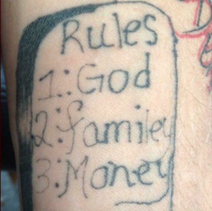 Poorly done tattoo listing "Rules: 1. God, 2. Family, 3. Money" on a person's arm.