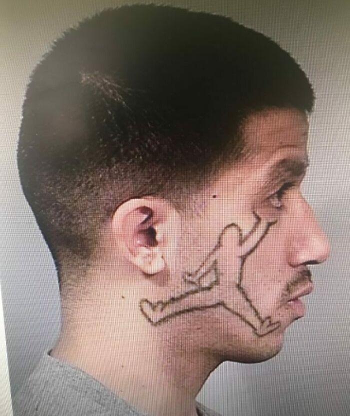 Profile of a man with a poorly done face tattoo resembling a jumping figure.
