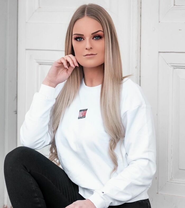 Young woman with long blonde hair wearing a white sweatshirt, representing Instagram Reality community exposing fake photos.