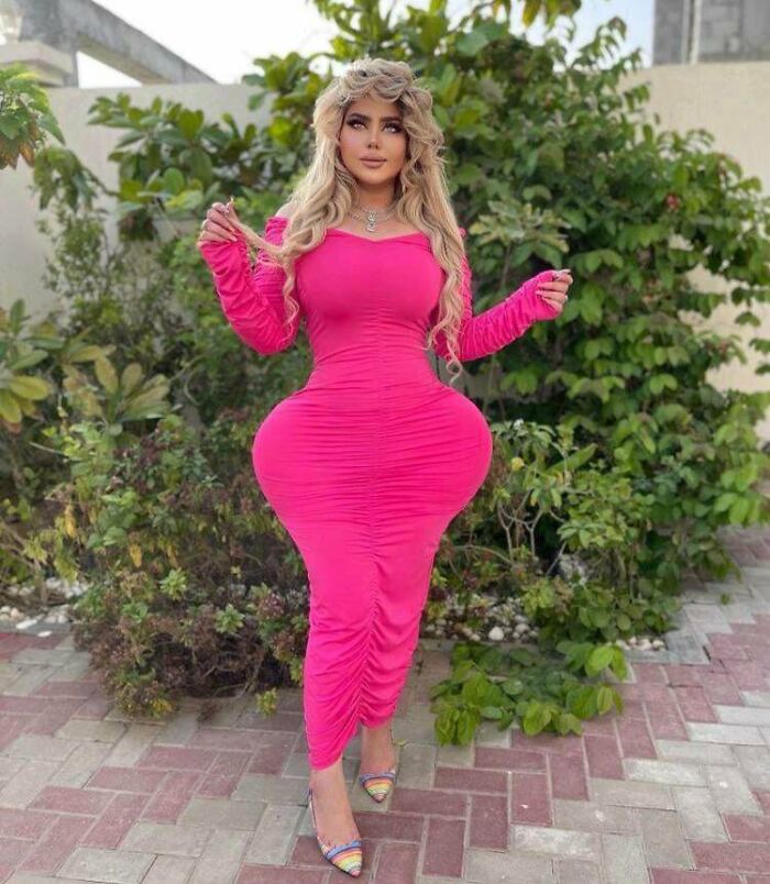 Woman in a bright pink dress with exaggerated silhouette standing outdoors, illustrating Instagram reality photo edits.