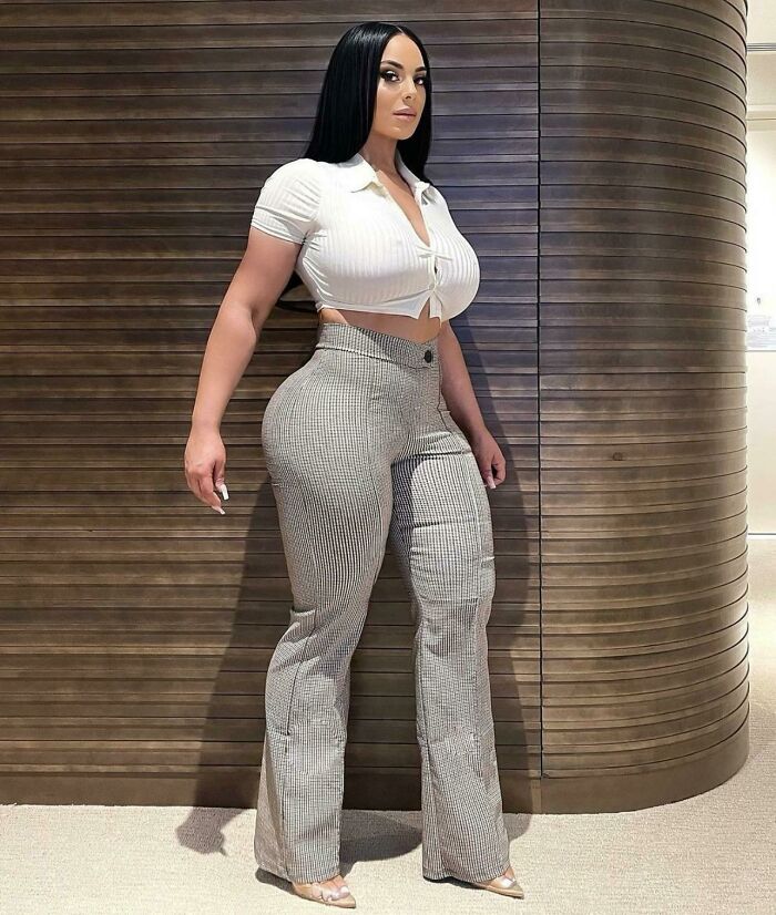 Woman posing indoors in fitted pants and cropped top, illustrating Instagram reality community exposing fakest photos online.