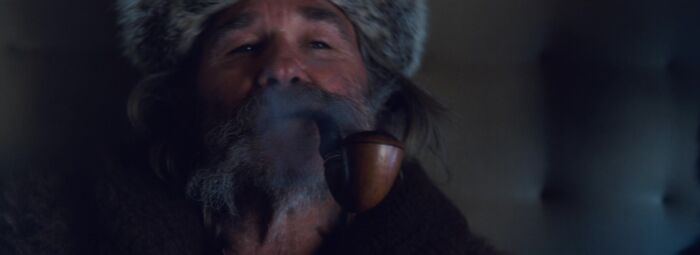 Close-up of an older man with a fur hat smoking a pipe, highlighting Easter eggs and hidden details from popular films.