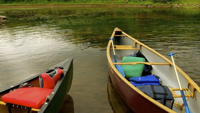 Two canoes docked on calm water with gear inside, illustrating peaceful outdoor scenes like startling windshield notes.