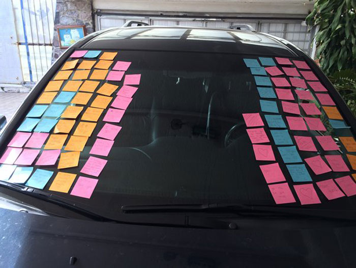 Car windshield covered with colorful sticky notes as a surprising example of startling windshield notes found by folks online.