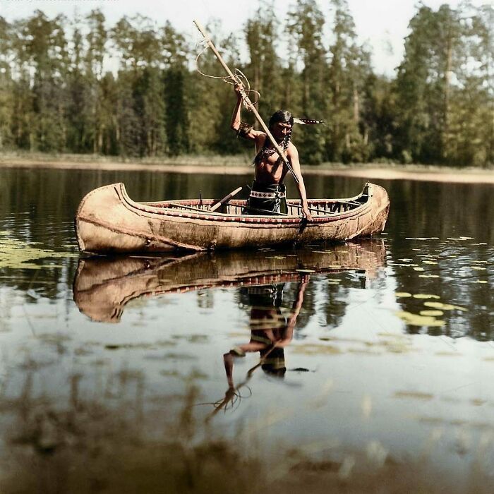 Un nativo americano, perteneciente al pueblo ojibwe, pescando con lanza en un lago de algún lugar de Minnesota, Estados Unidos. Fotografía tomada en 1908