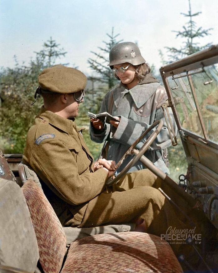 A Polish Servicewoman In German Uniform Checking The Identity Card Of Driver William Massey Of The Royal Canadian Army Service Corps At The Main Gate Of A German Prisoner-Of-War Camp For Female Personnel Of The Polish Army, Located North Of Haren, Germany. Photograph Taken On 7 May 1945