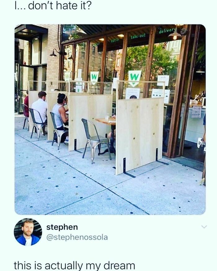 Outdoor restaurant seating with wooden dividers between tables, illustrating introvert nation meme about personal space.