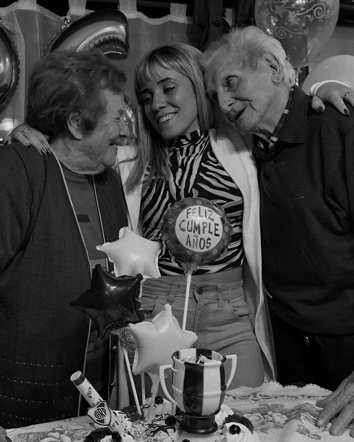 Grandparents' emotional reaction to girl's tattoo at a birthday celebration with balloons and a cake.