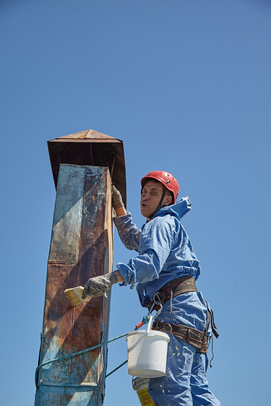 The Painter-Climber Paints The Chimney. A Worker On A Blue Sky Background.