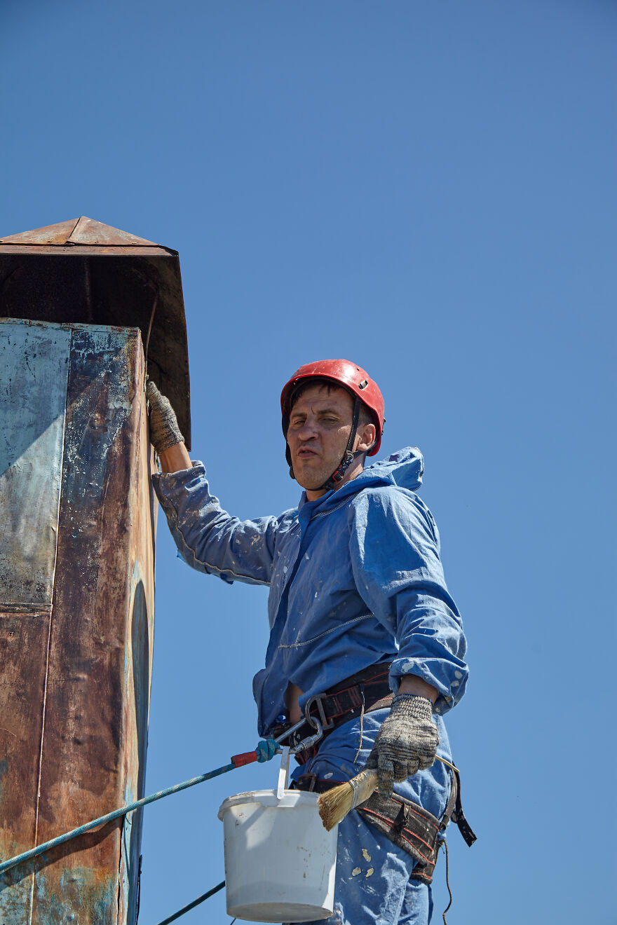 The Painter-Climber Paints The Chimney. A Worker On A Blue Sky Background.