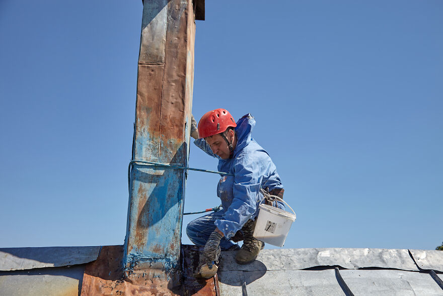 The Painter-Climber Paints The Chimney. A Worker On A Blue Sky Background.