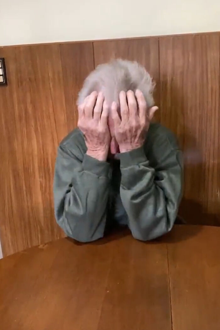Elderly person covering face with hands, reacting emotionally to girl's tattoo news.