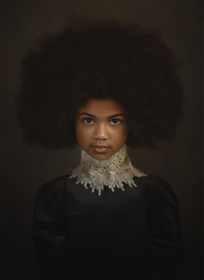 Portrait of a young girl with natural afro hairstyle and ornate lace collar, showcasing powerful photography at Siena Photo Awards.