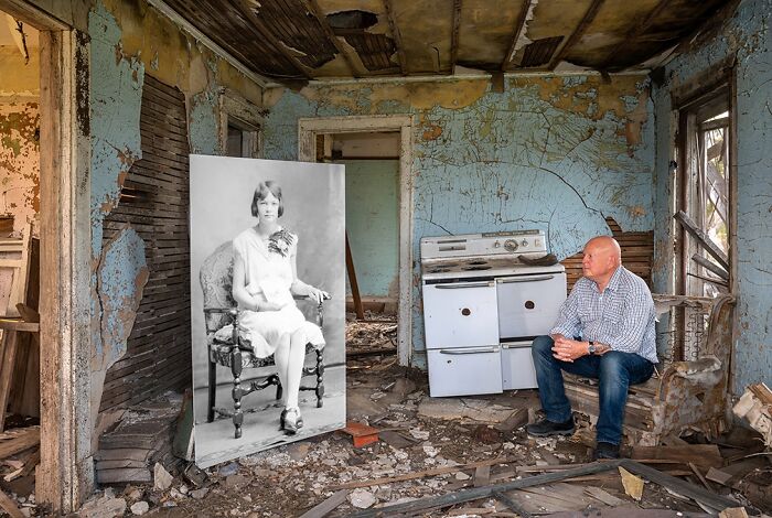 Man sitting in a dilapidated room looking at a large vintage black and white photo, powerful photography winning image concept.