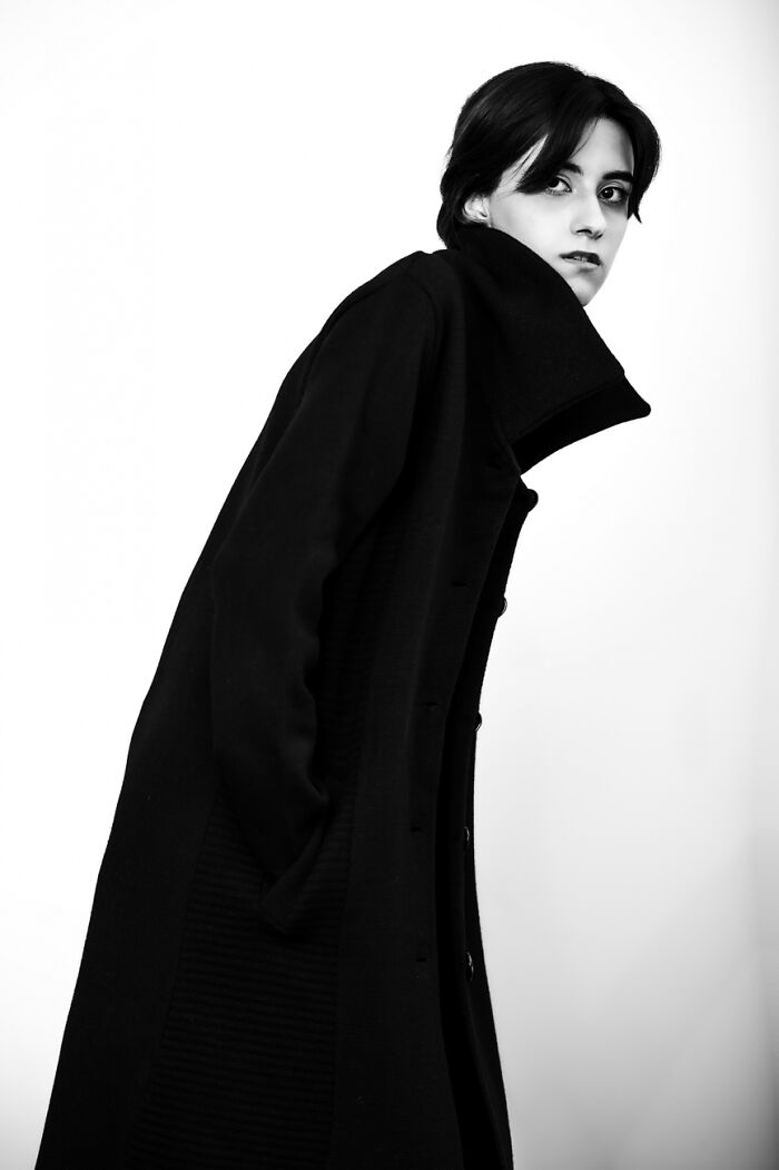 Black and white powerful photography portrait of a person in a long coat with high collar and intense expression