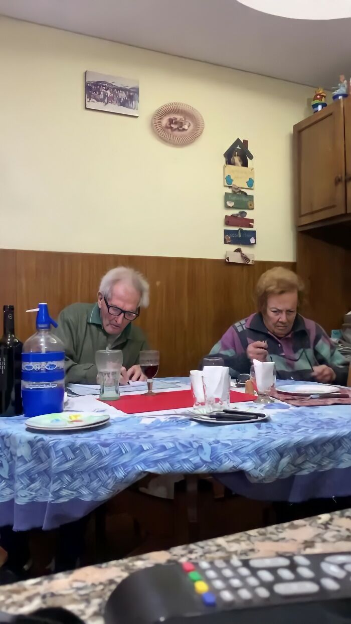 Elderly couple at a dining table, illustrating grandparents' emotional reaction in a cozy home setting.