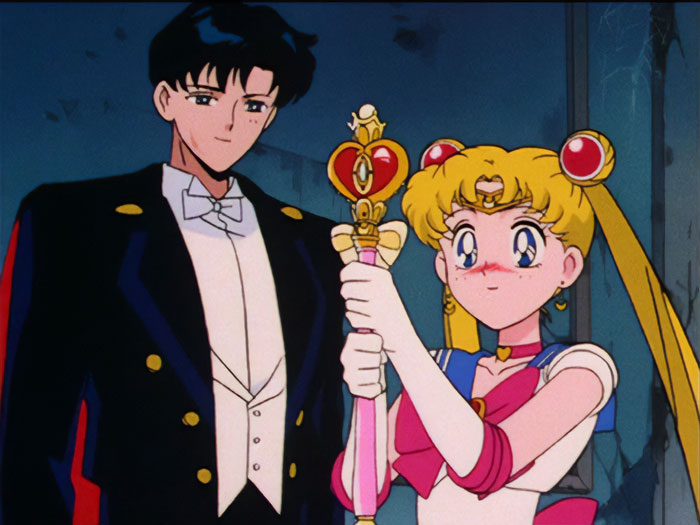 Anime couple in formal attire with a staff, showcasing one of the cutest pairings from fan choices.