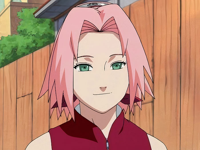 Anime character with pink hair and green eyes, wearing a red top, standing outdoors, embodying favorite female anime traits.