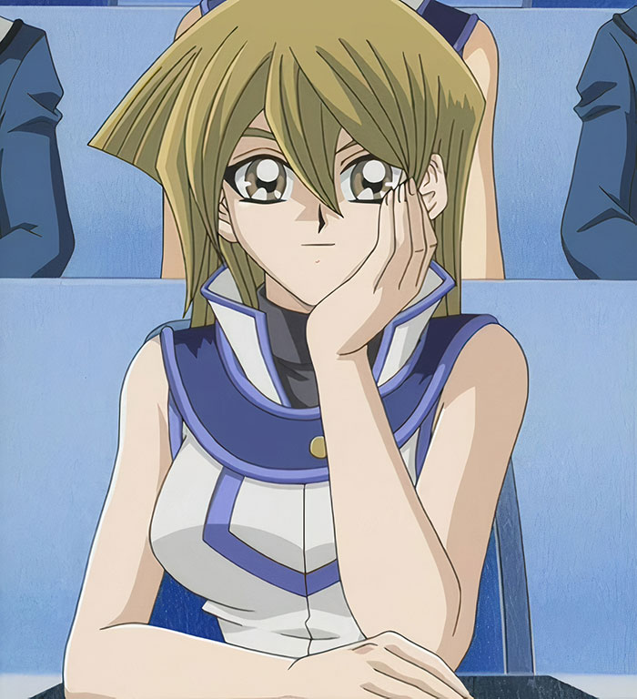Female anime character with blonde hair sitting in a blue uniform, resting her head on her hand.