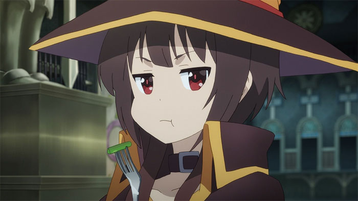 Anime character in a witch outfit holding a fork with a vegetable, displaying a pouting expression.