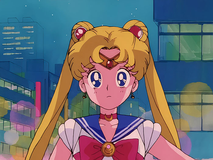 Iconic female anime character in a sailor outfit stands in a cityscape at night.