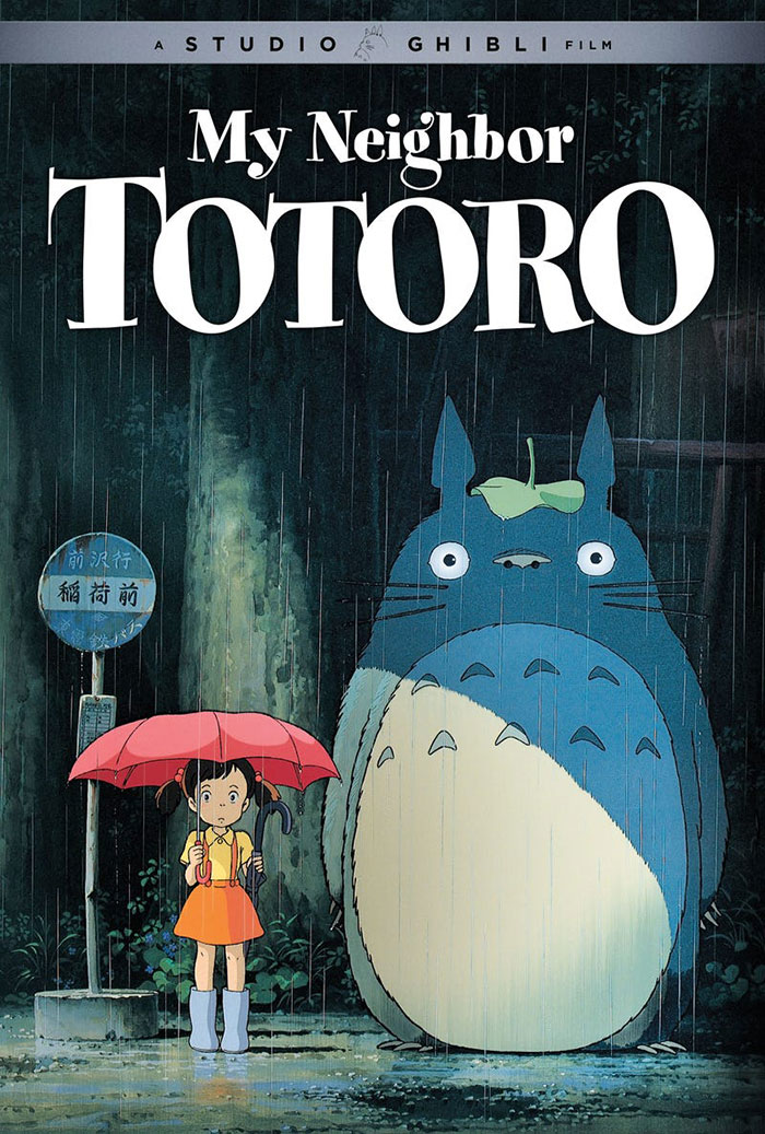 Anime for kids: A girl with an umbrella stands next to a large creature in the rain from "My Neighbor Totoro" scene.