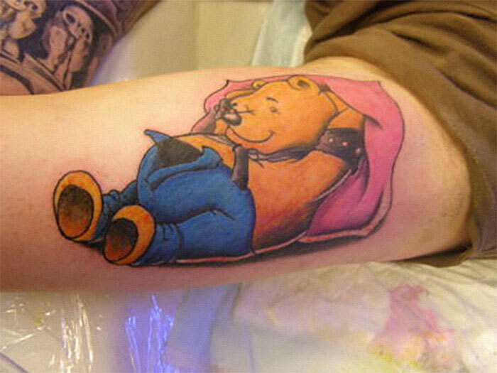 Tattoo of a cartoon bear wearing a harness and wrapped in a pink blanket; seen as a potential red flag by some people.