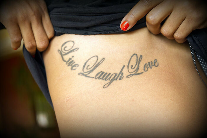 "Live Laugh Love tattoo on side of a person's body, often considered a red flag by some people."
