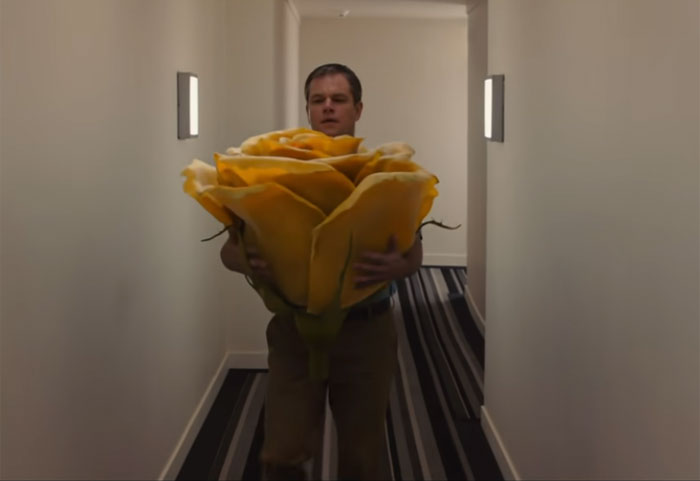 Man holding an oversized yellow rose walking down a narrow hallway, representing movies people couldn’t finish.