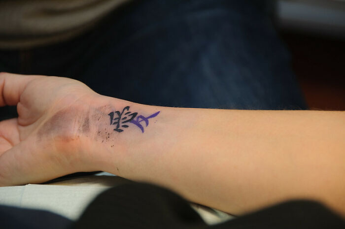 Wrist tattoo with black and purple ink, considered by some as a red flag.