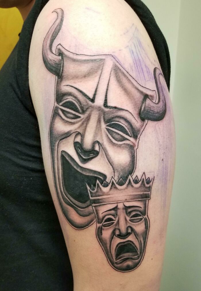 Theatrical masks tattoo with horns and crown, noted as a red flag design.