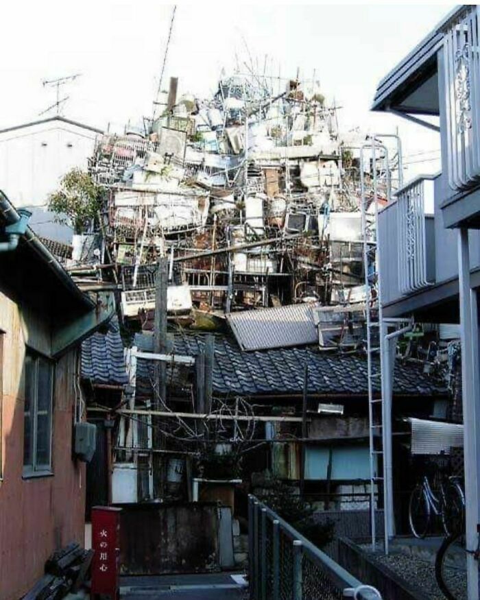 Bizarre buildings stacked with various metal and household items creating a chaotic and unique architectural structure.