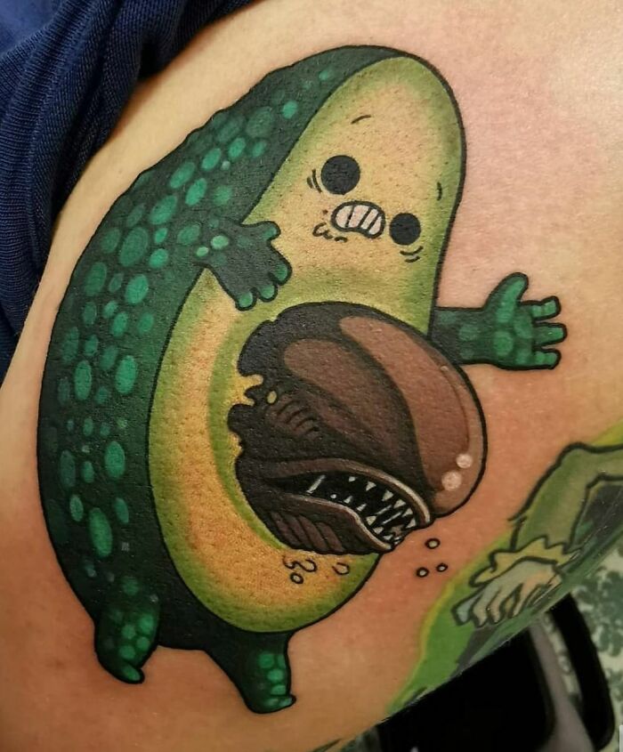 Crazy tattoo of a cartoon avocado with a monster coming out, showcasing unique ink creativity.