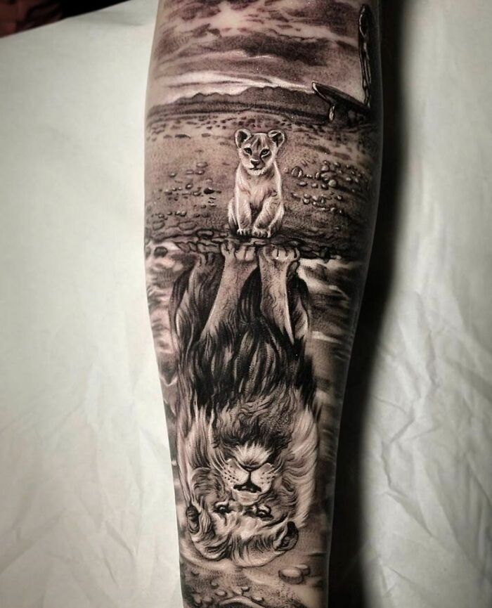 Lion and cub tattoo with reflection, showcasing crazy tattoo creativity on a forearm.