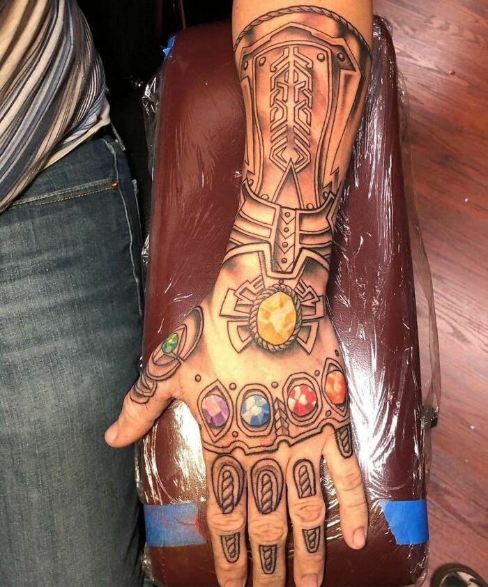 Arm tattoo designed like a gauntlet with colorful gem-like details, showcasing a creative tattoo choice.