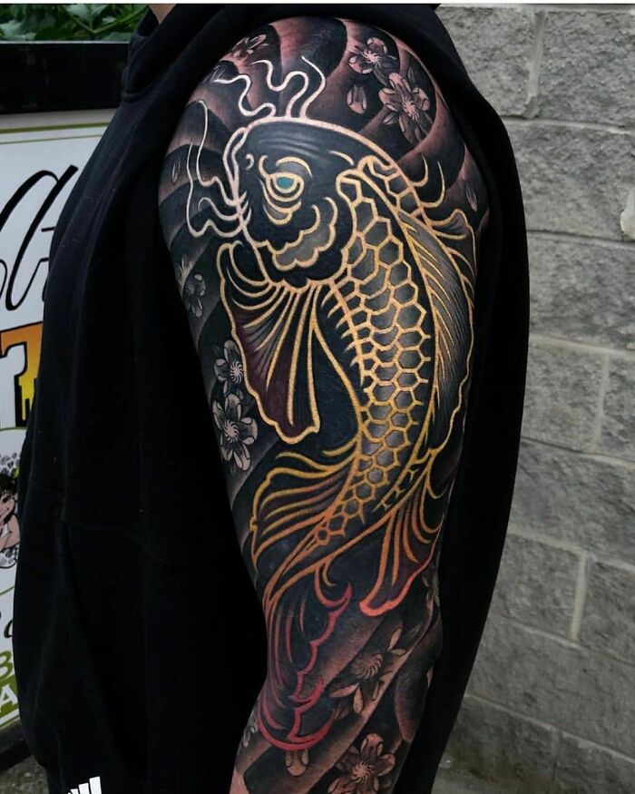 Intricate koi fish tattoo on arm with vibrant colors and floral details.