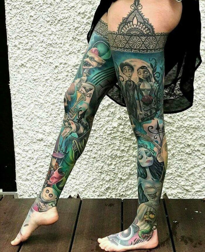 Colorful tattoos cover a person's legs, showcasing intricate and creative designs.