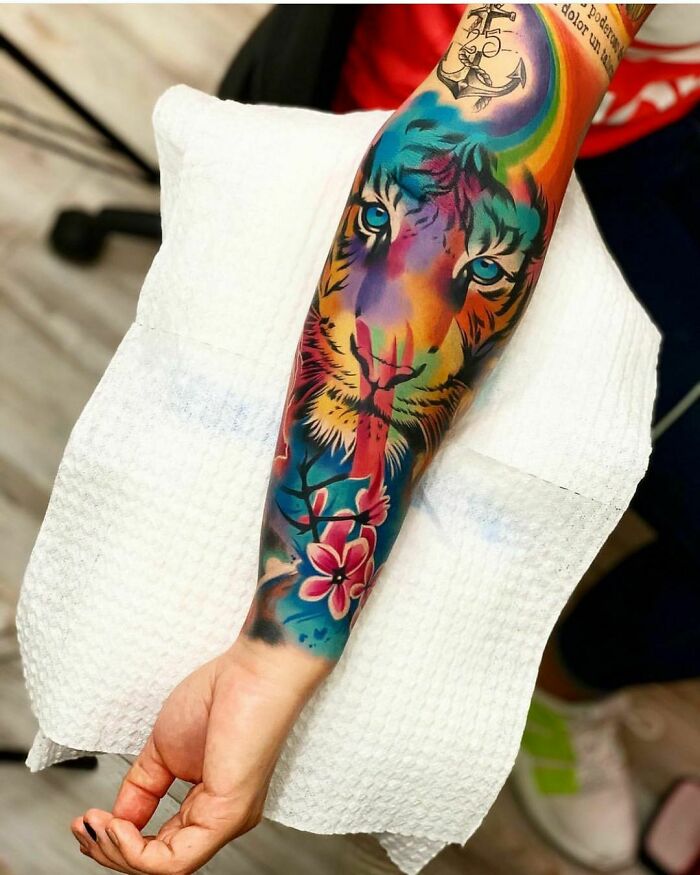 Colorful tiger tattoo with flowers on arm showing unique ink design.