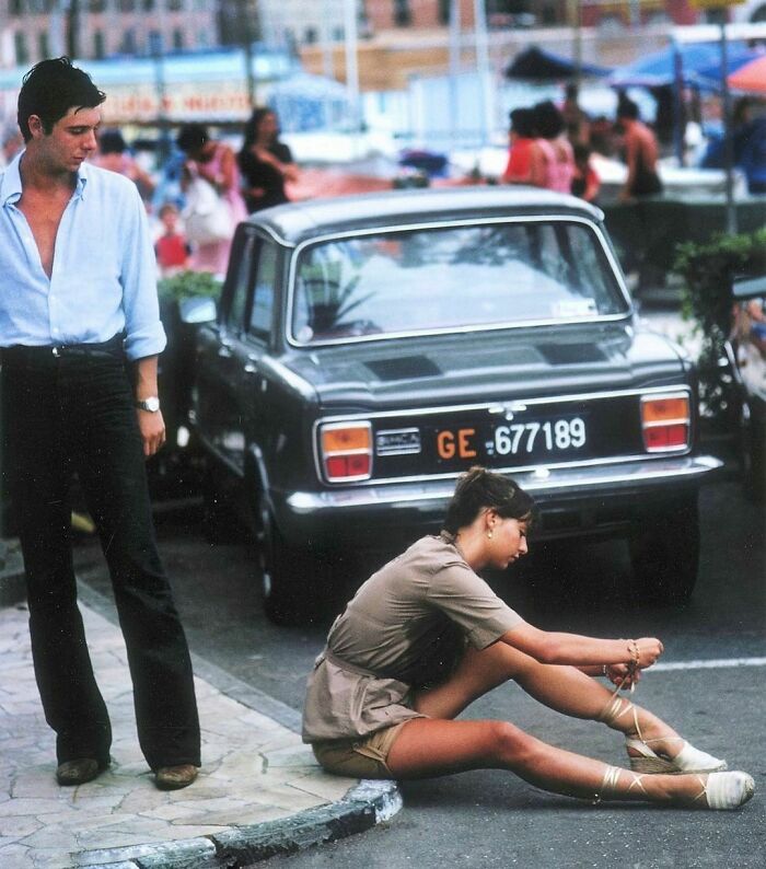 A Man Stops To Watch A Woman Tie Her Sandals In Portofino Marina, August 1977 (Photo By @slim.aarons