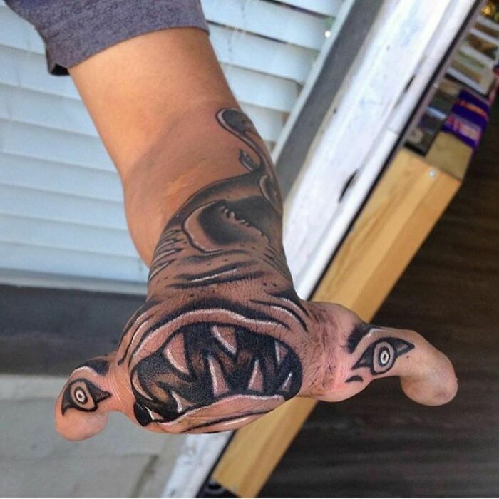 Arm with a unique, bold tattoo resembling an animal face, showcasing creative tattoo artistry.