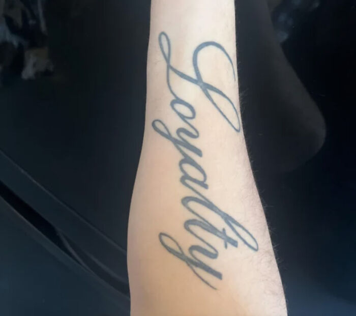 Tattoo of the word "Loyalty" on a forearm, highlighting potential red flags associated with certain tattoos.