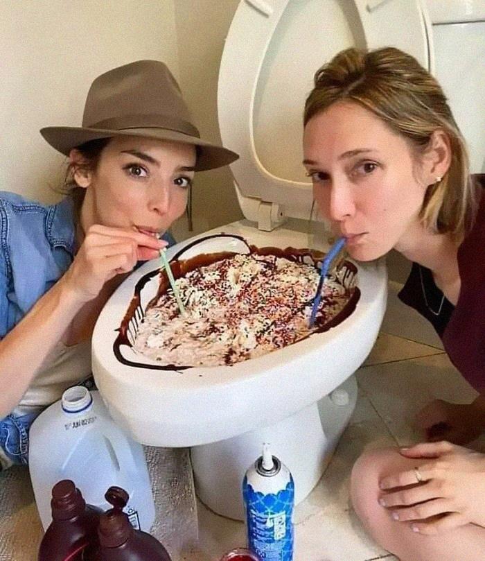 Two women drinking dessert with straws from a toilet bowl repurposed as a food container, an example of food with threatening auras.