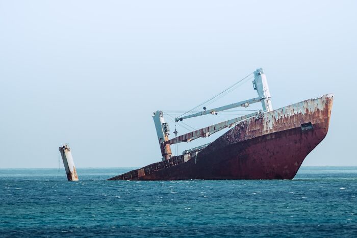 Rusty shipwreck partially submerged in the ocean, illustrating one of the creepiest facts about the ocean environment. - 11