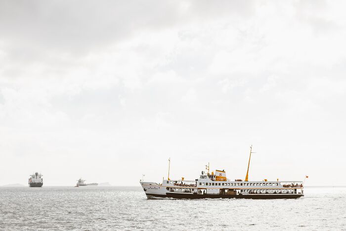 Passenger ferry and cargo ships on a calm ocean under a cloudy sky, illustrating creepy facts about the ocean. - 19