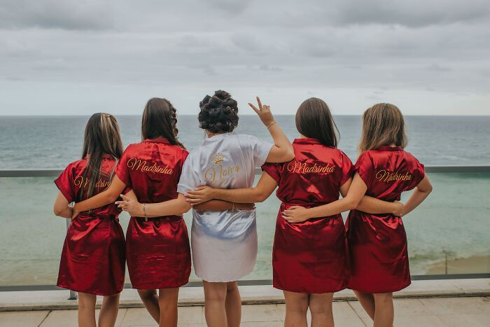Bride and bridesmaids in robes by the ocean, illustrating one of the weirdest wedding experiences shared online.
