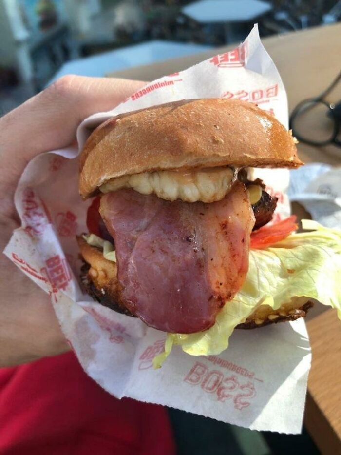 Close-up of a burger with bacon and lettuce, one of the worst examples of food with threatening auras shared online.