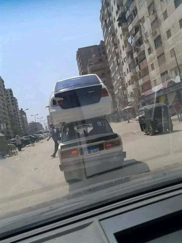 Two cars stacked on top of each other on a city street, showcasing an example of bad drivers spotted in a public area.