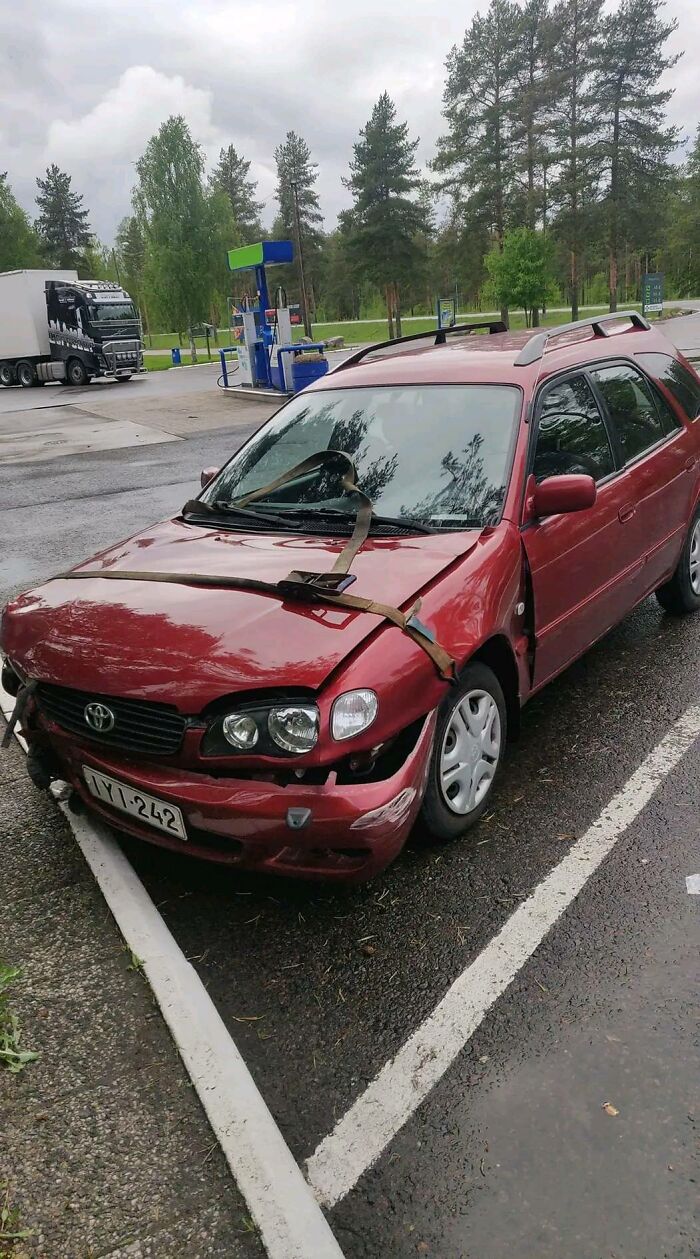 Red Toyota car with severe front-end damage held together by straps in a parking lot, example of bad drivers documented online.